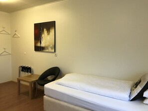 A bedroom with a bed, a desk, and a chair. There is a painting on the wall. - Hotel Hvammstangi (Hvammstangi)