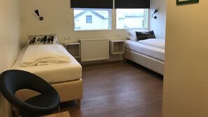 A small, tidy room with two beds, a chair, and a radiator. - Hotel Hvammstangi (Hvammstangi)