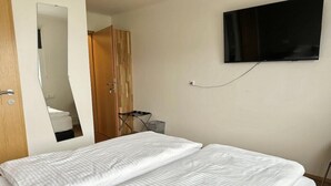 A hotel room with a bed, a TV mounted on the wall, and a wooden wardrobe. - Hotel Hvammstangi (Hvammstangi)
