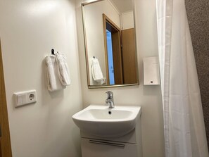 A bathroom with a white sink, a mirror, and two towels hanging on hooks. - Hotel Hvammstangi (Hvammstangi)
