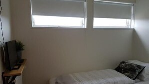 A small, single-bed room with a desk and a TV. There are two windows providing natural light. - Hotel Hvammstangi (Hvammstangi)