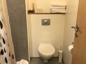 Ein kleines Badezimmer mit Toilette, Handtuchhalter und Toilettenpapierhalter.