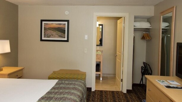 A hotel room with a bed, a desk, a chair, a wardrobe, and a bathroom visible through an open door. - Bar Harbor Villager Motel (Bar Harbor)