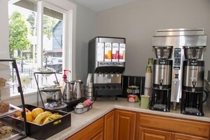 Una cocina con una exhibición de frutas, máquinas de café y una estación para café.