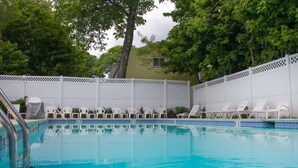 A swimming pool with white lounge chairs and a white fence. - Bar Harbor Villager Motel (Bar Harbor)