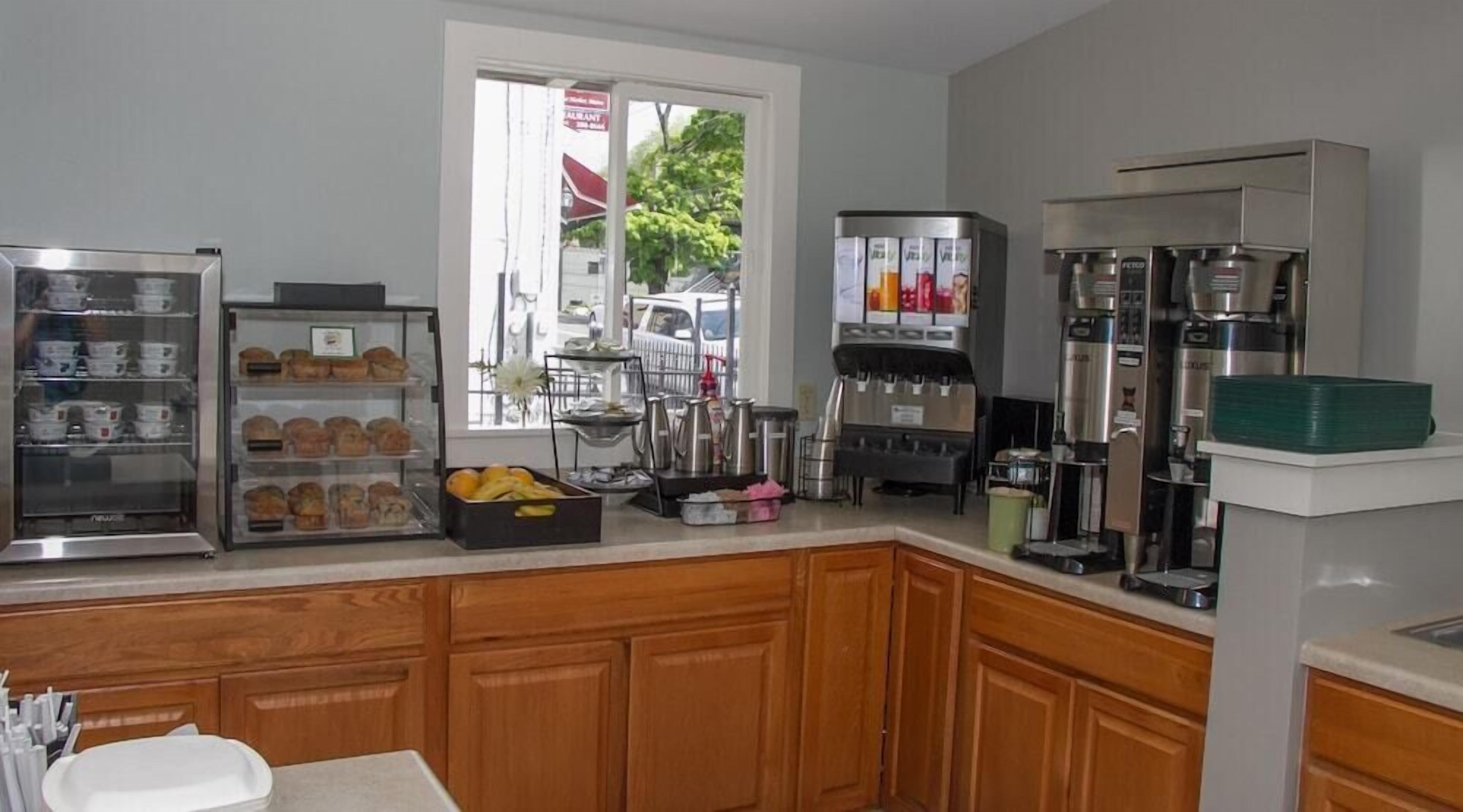 A kitchen with a display case of pastries, a coffee machine, and a fruit bowl.