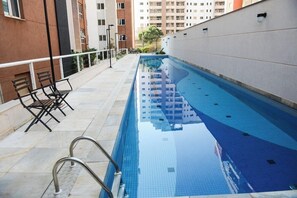 Ein Hallenbad mit glasklarer Wasserfläche, umgeben von einer gefliesten Liegefläche und Metallgeländern.