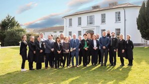 A group of people standing in front of a white building with a symmetrical facade and multiple windows. - Springfort Hall Hotel (Mallow)