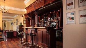 A bar area with wooden paneling, a chandelier, and bar stools. - Springfort Hall Hotel (Mallow)