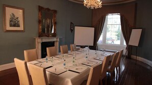A conference room with a long table, chairs, a fireplace, a chandelier, a large window, and a whiteboard. - Springfort Hall Hotel (Mallow)