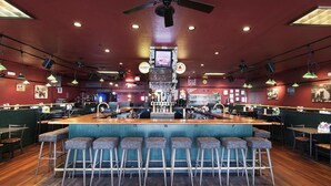 A bar area with a central bar counter, multiple stools, and overhead lighting. - Westmark Inn Skagway (Skagway)