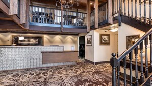 A spacious lobby with a reception desk, patterned carpet, and a staircase leading to an upper level. - Westmark Inn Skagway (Skagway)