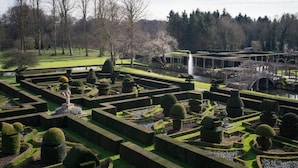 A formal garden with geometric hedges, a central water feature, and a bridge. - Great Fosters (Egham)