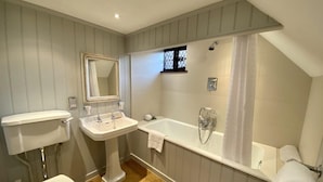 A bathroom with a toilet, pedestal sink, vanity, bathtub, and a window with a view. - Great Fosters (Egham)