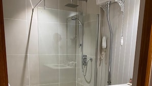 A modern bathroom with a glass-enclosed shower, a wooden toilet, and a white sink. - Great Fosters (Egham)
