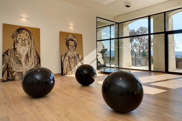 A modern interior with wooden flooring, large black spherical sculptures, and two classical statues. - Coquillade Village (Gargas)