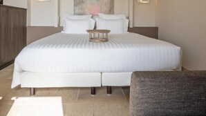A modern hotel room with a large bed, a painting on the wall, and two wall-mounted lights. - Coquillade Village (Gargas)