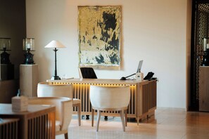Un comptoir d’accueil avec une lampe, des chaises et un tableau accroché au mur.