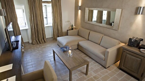 A modern living room with a sofa, a coffee table with a candle, a TV, and a wooden cabinet. - Coquillade Village (Gargas)