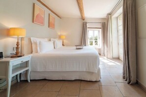Une chambre à coucher avec un grand lit, des tables de chevet, un bureau et une fenêtre avec des rideaux.