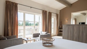 A spacious room with a large bed, a dining area, and a view of the outdoors. - Coquillade Village (Gargas)