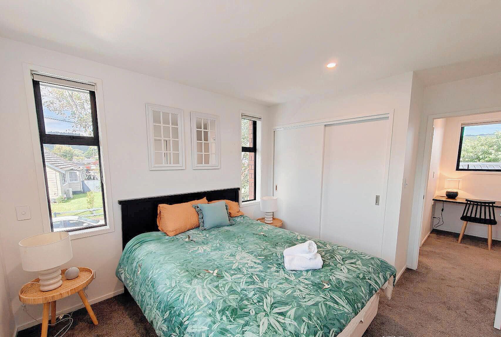 A bedroom with a bed, a desk, and a wardrobe.