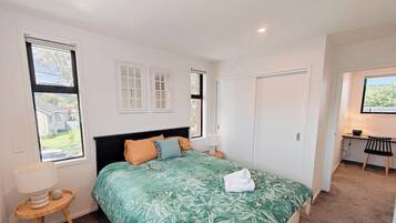 A bedroom with a bed, a desk, and a wardrobe.