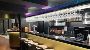 A bar area with a counter, bar stools, a wine rack, and a coffee machine. - Brit Hotel Le Relais du Ried (Bischwihr)