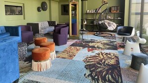 A modern living room with a sofa, armchairs, ottomans, a hanging chair, and a bookshelf. - Brit Hotel Le Relais du Ried (Bischwihr)