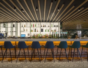 A bar area with a long counter, multiple stools, and a variety of bottles. - Pillo Hotel Ashbourne (Ashbourne)