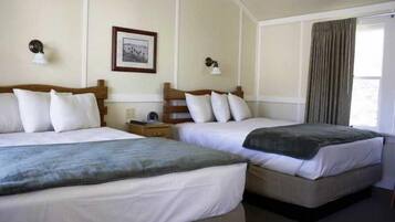 A hotel room with two beds, a framed picture on the wall, and a window with curtains.