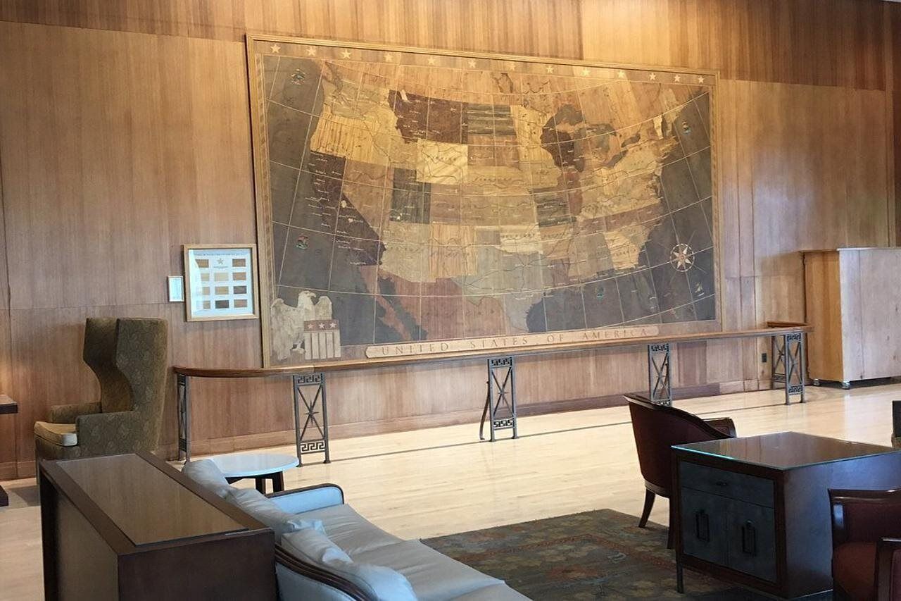A lobby with a large map of the United States, a sofa, a chair, and a small table.