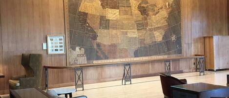 A lobby with a large map of the United States, a sofa, a chair, and a small table.