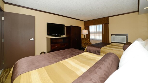 Habitación de hotel con dos camas, televisión, escritorio y ventana con cortinas.