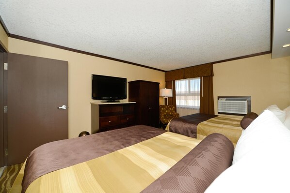 Ein Hotelzimmer mit zwei Betten, einem Fernseher, einem Schreibtisch und einem Fenster mit Vorhängen.