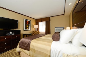 Ein Hotelzimmer mit Bett, Fernseher, Schreibtisch und Stuhl.