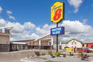 Un hotel Super 8 con tobogán de agua, arquitectura moderna y cielo despejado.