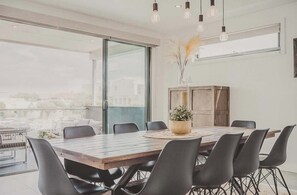 Un comedor moderno con una mesa de madera y sillas negras, ventanas amplias y vistas a la ciudad.
