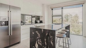 A modern kitchen with a large island, stainless steel appliances, and a view of the outdoors.
