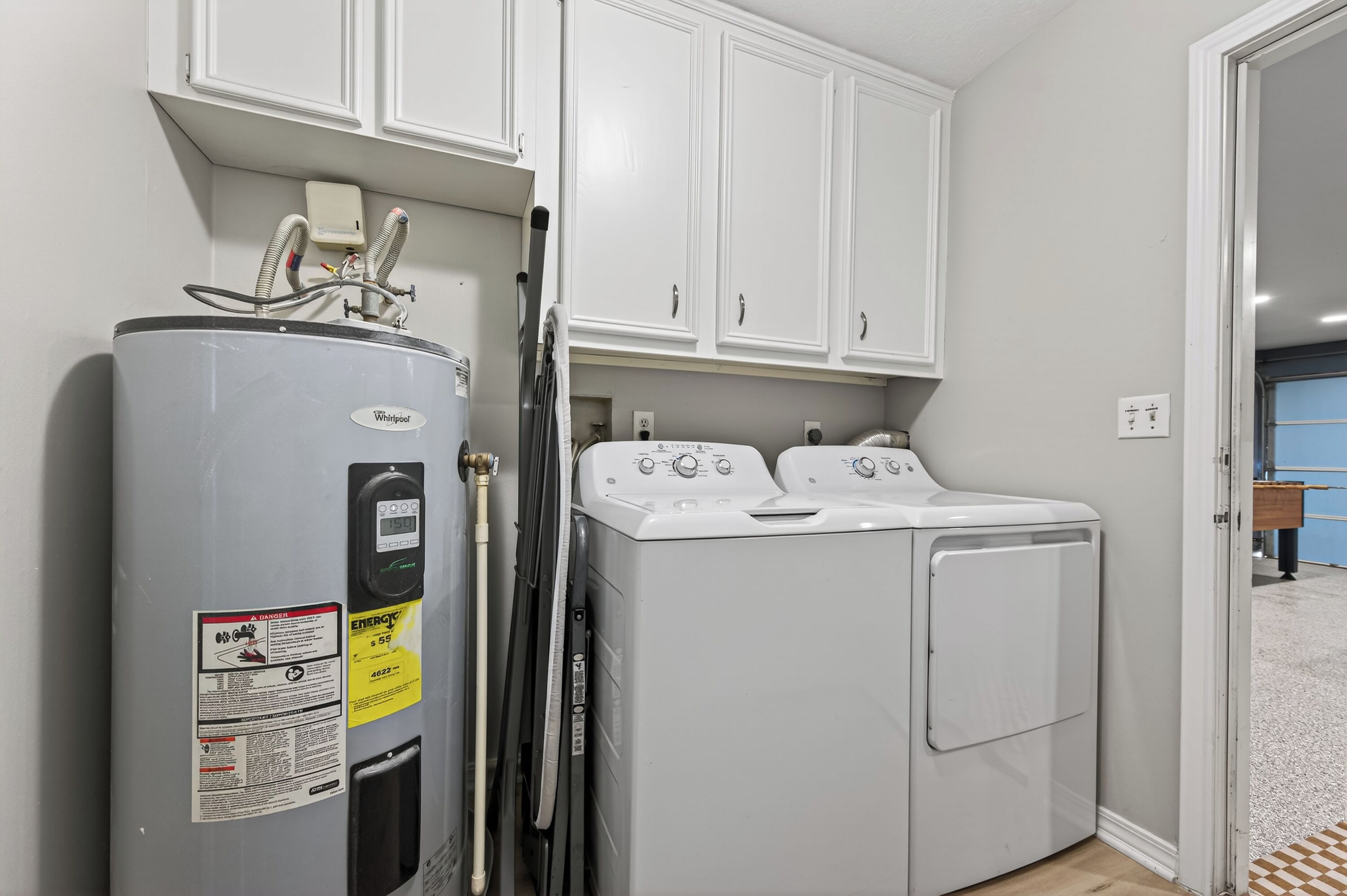 A laundry room with a Whirlpool washer and dryer, a water heater, and a utility meter.