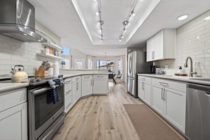 A modern kitchen with stainless steel appliances, white cabinetry, and a central island.