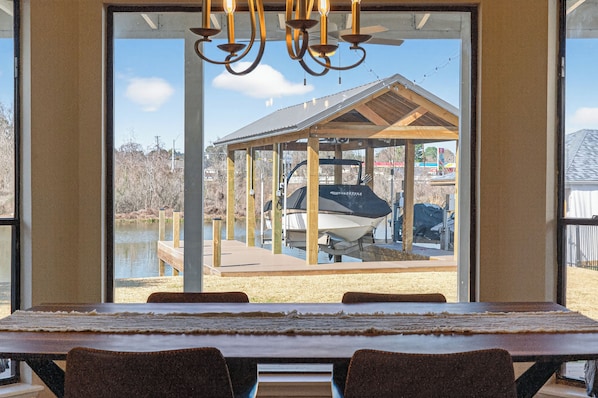 A dining area with a view of a dock and a boat.