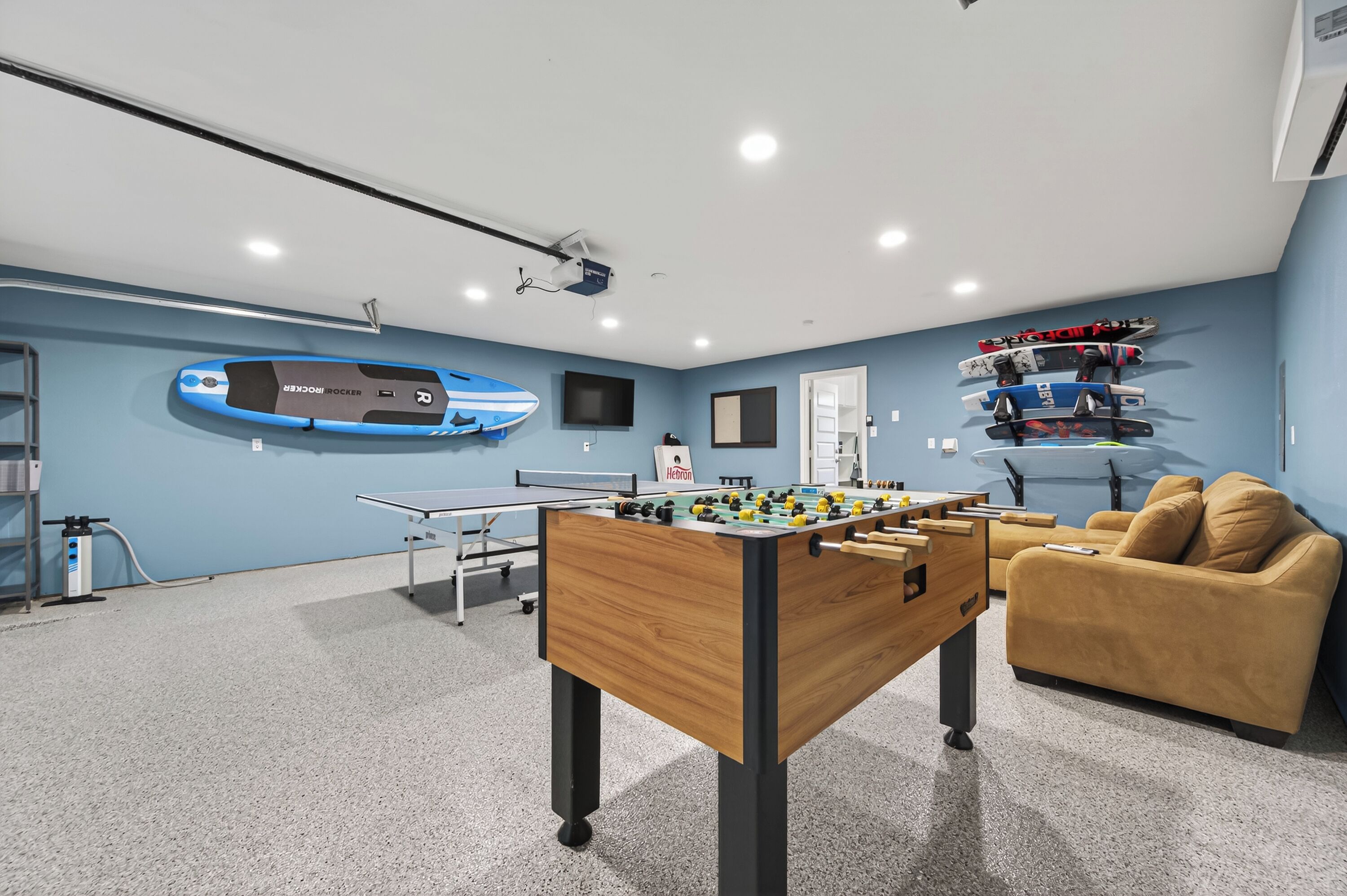 Ein Zimmer mit Kicker, Tischtennisplatte und einem Kicker mit blau-schwarzem Design.