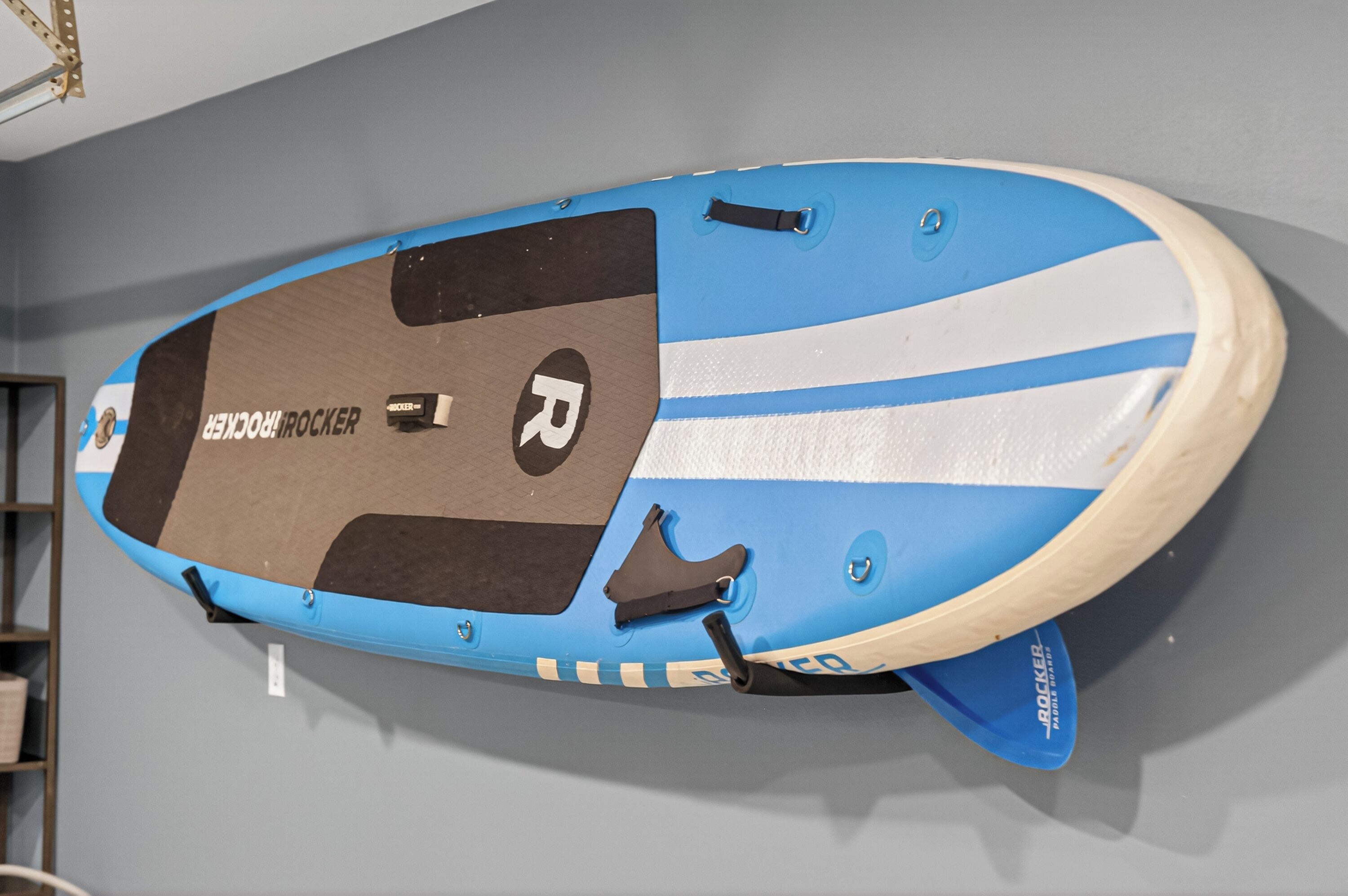 A blue and white surfboard with the text "ROCKER" and "ROCKER" on the side, mounted on a wall.