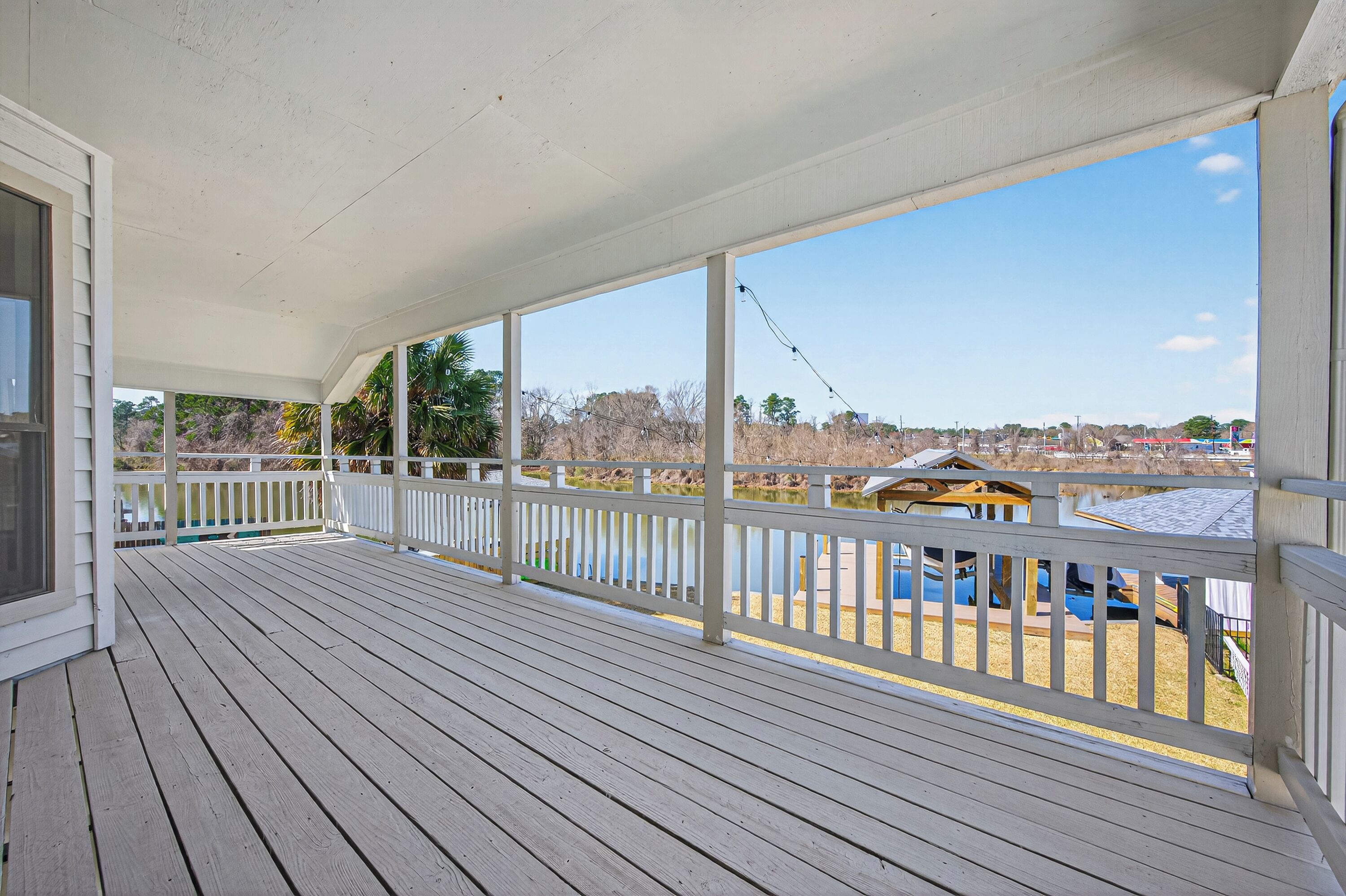 A wooden deck with a white railing, overlooking a playground with a yellow structure.