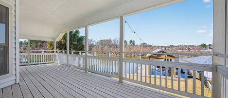 A wooden deck with a white railing, overlooking a playground with a yellow structure.