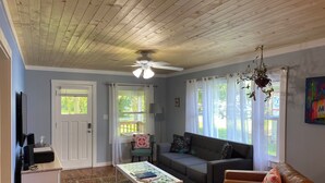A living room with a ceiling fan, a sofa, a coffee table, and a television. - Crabapple Cottage (Essex)