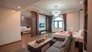 A modern hotel room with a sofa, a TV, a bed with a red rose decoration, and a large window. - Vela Luxury Hai Ha Hotel  (Quang Ha)