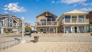 A beachfront property with a stone facade, multiple balconies, and outdoor seating.
