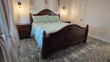 Une chambre à coucher avec un lit en bois, un ventilateur de plafond, un tapis à motifs et des lampes fixées au mur.